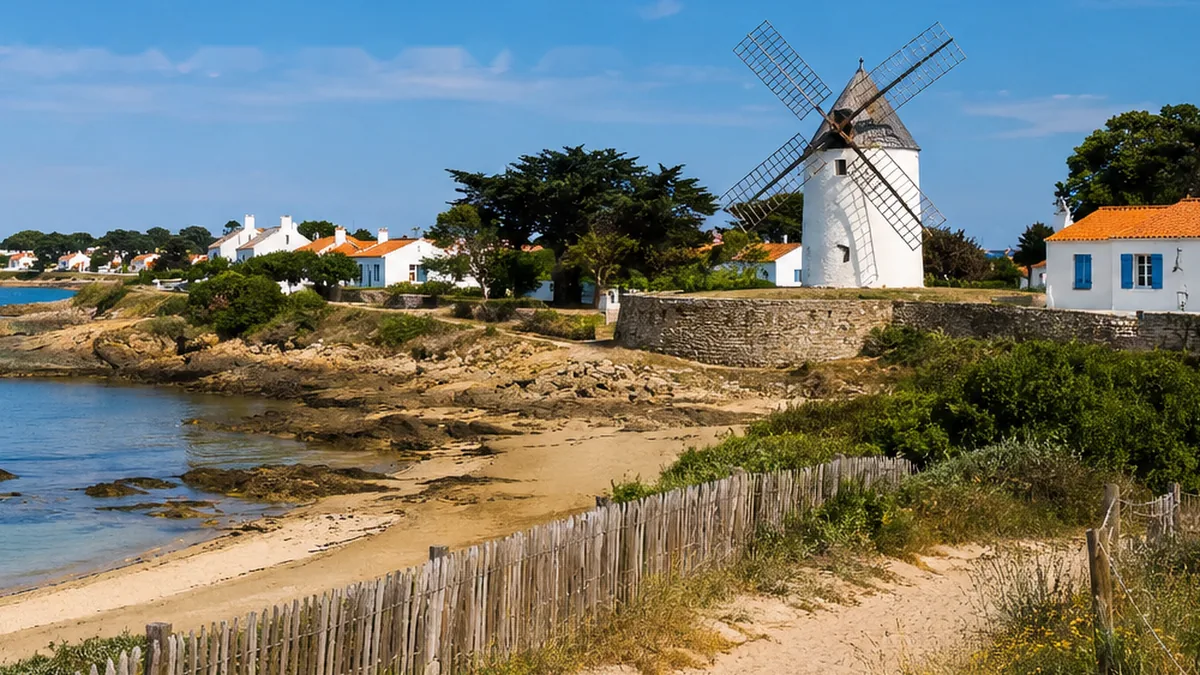 Moulin blanc et maison aux volets bleus au bord d’une plage de Noirmoutier