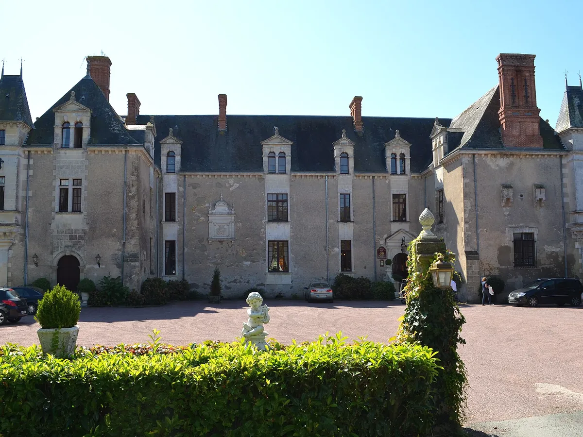 Façade du château de la Vérie à Challans : un logis en pierre aux hautes lucarnes et aux toits d'ardoise, devant une cour gravillonnée et une haie taillée