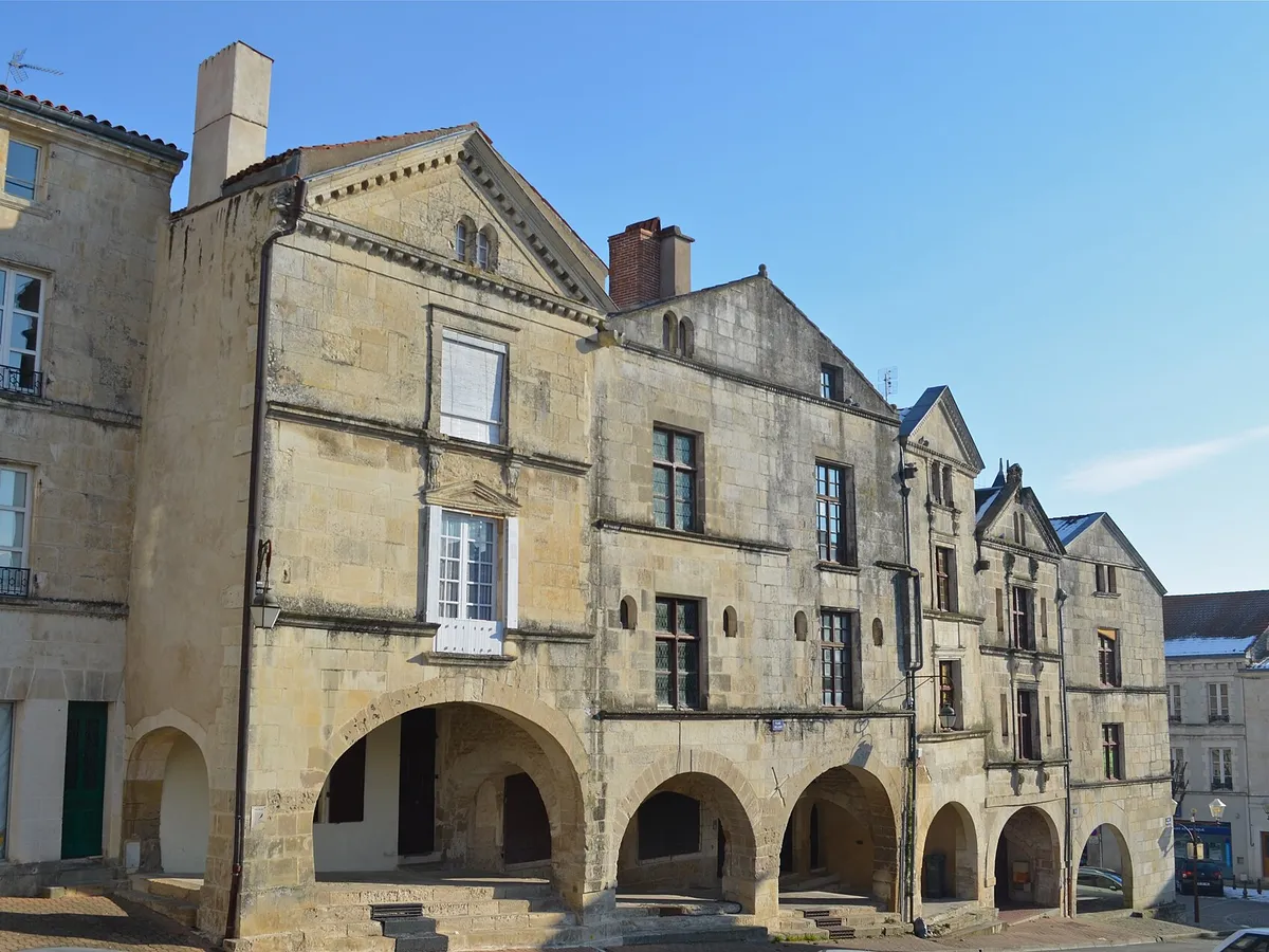 Maisons anciennes à arcades de la place Belliard, à Fontenay-le-Comte, sous un ciel bleu