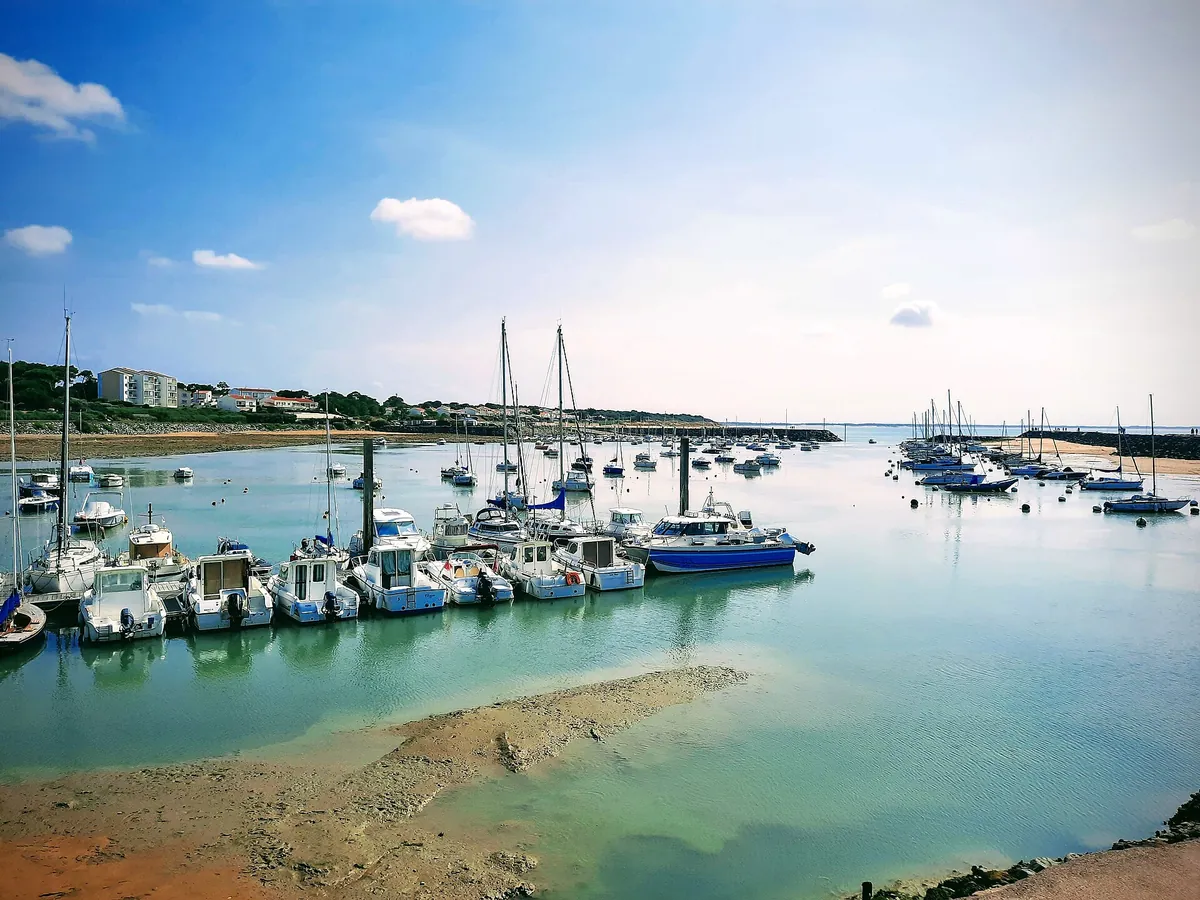 Le port de plaisance de Jard-sur-Mer à marée basse, avec des voiliers et des bateaux amarrés sur une eau turquoise