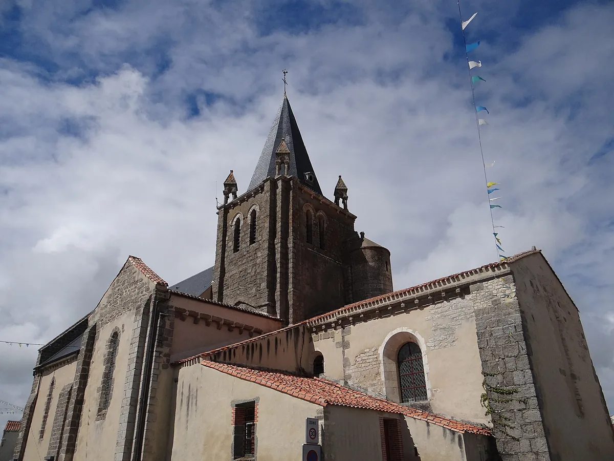 L'église Notre-Dame-de-l'Assomption de Longeville-sur-Mer, avec son clocher de pierre coiffé d'une flèche, sous un ciel nuageux