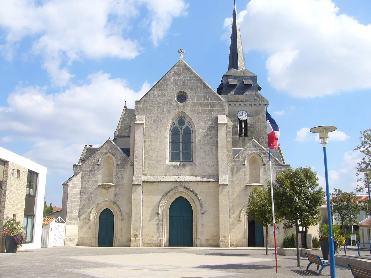 Église Saint-Hilaire de Saint-Hilaire-de-Riez, en pierre claire avec son clocher à flèche, sur une place pavée du bourg