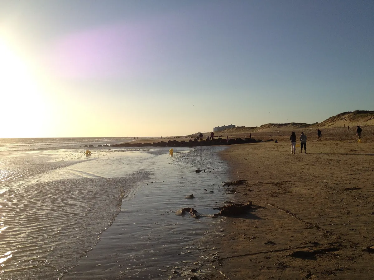 Plage de sable des Mouettes à Saint-Hilaire-de-Riez en fin de journée, avec des dunes et quelques promeneurs au loin