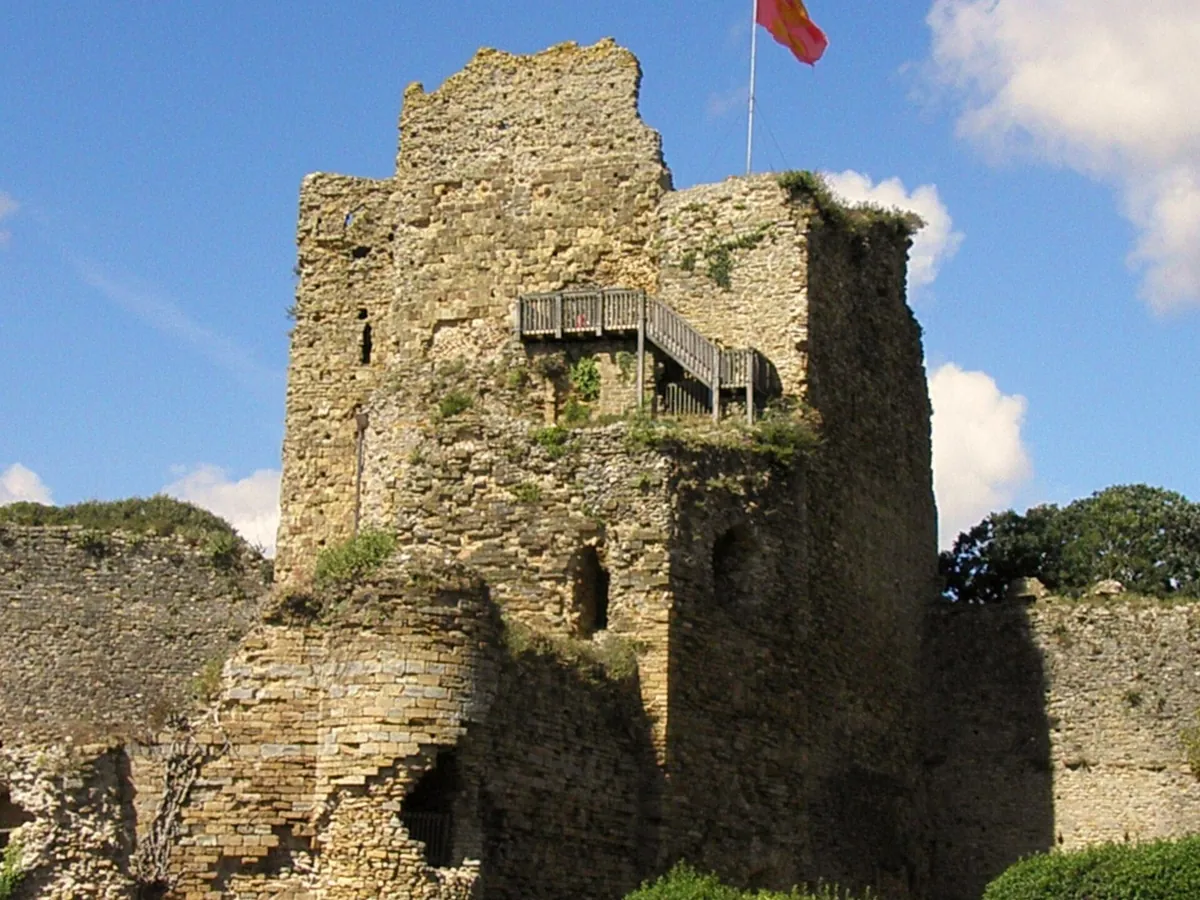 Tour en ruine du château de Talmont, avec un escalier en bois, un drapeau et des remparts, sous un ciel bleu